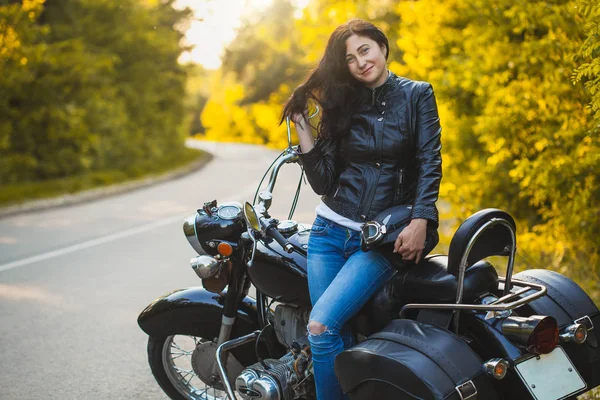 Attraktive brünette Motorradfahrerin sitzt auf einem Motorrad. — Stockfoto