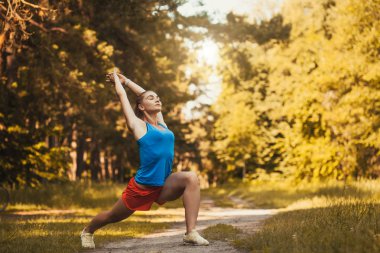Ormanda koşu önce egzersizleri yapan güzel kadın atlet