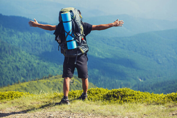 A tourist walks along a mountain meandering trail. Summer walking in mountains