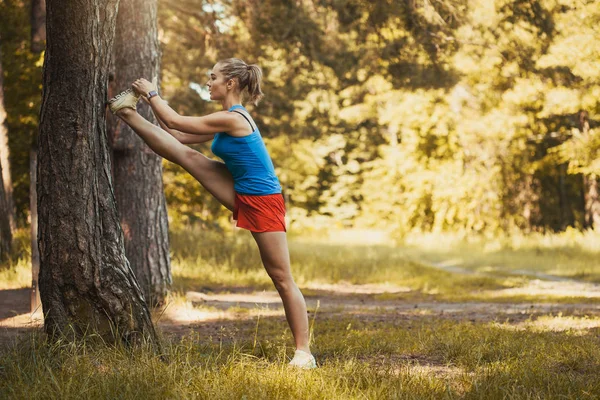 Atlet wanita cantik melakukan latihan sebelum joging melalui hutan — Stok Foto