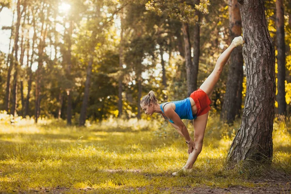 Ung kvinna värmer upp innan du springer i skogen på en vacker sommardag — Stockfoto