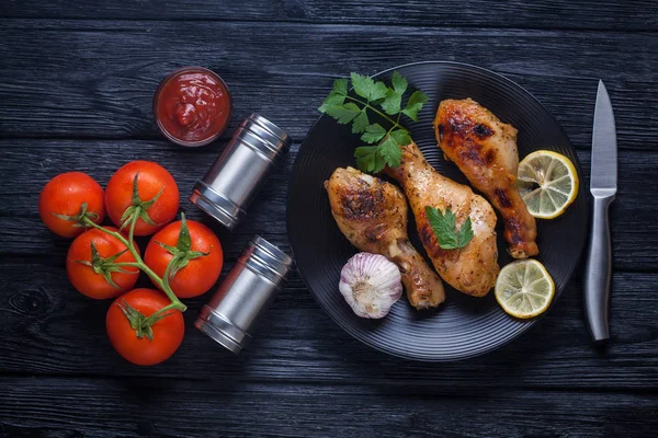 Πόδια κοτόπουλου με ντομάτες, λεμόνι, μαϊντανό και κέτσαπ σε μαύρο πιάτο — Φωτογραφία Αρχείου