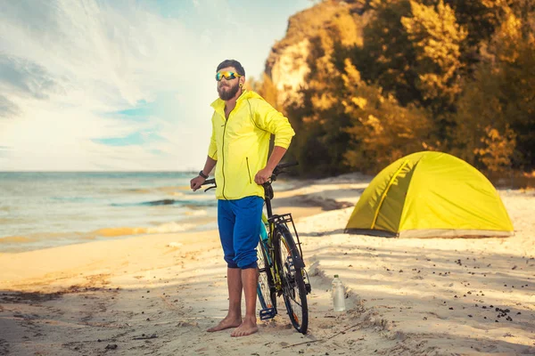 Bearded man resting with a tent on a sandy beach. — Stock Photo, Image