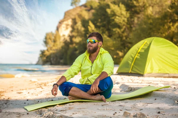 Brodaty człowiek odpoczynku z namiotu na piaszczystej plaży. — Zdjęcie stockowe