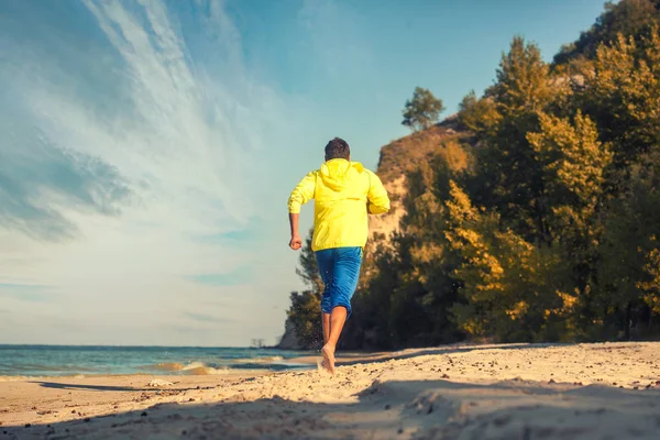 bearded athlete runs along the sandy beach.