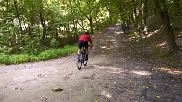 Joven ciclismo en un camino forestal en un día de verano — Vídeo de stock