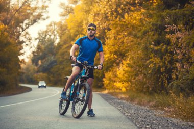 Sakallı adam dağ bisikletiyle ormanda bisiklet sürüyor..