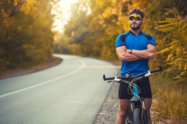 Sakallı adam dağ bisikletiyle ormanda bisiklet sürüyor..