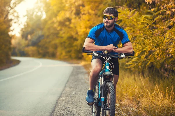 Brodaty człowiek rowerzysta jeździ w lesie na rowerze górskim. — Zdjęcie stockowe