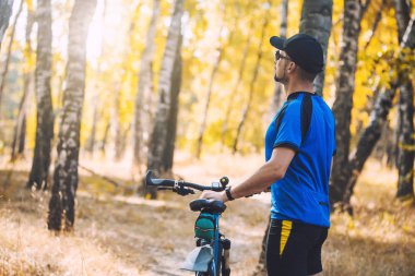 Sakallı adam dağ bisikletiyle ormanda bisiklet sürüyor..