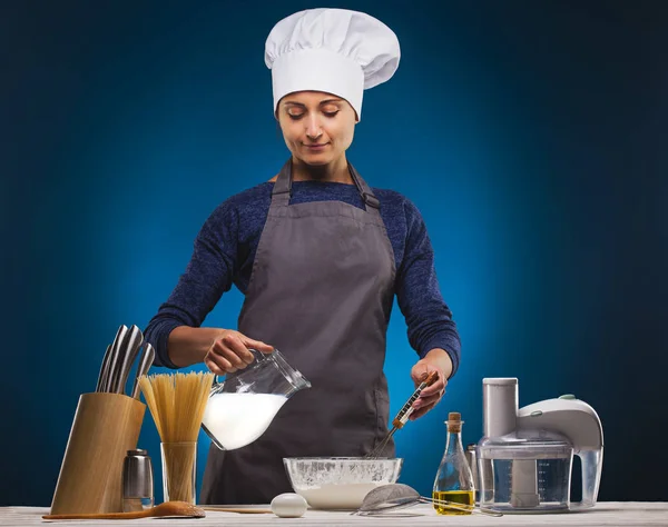 Женщина-повар готовит вкусное блюдо на голубом фоне . — стоковое фото