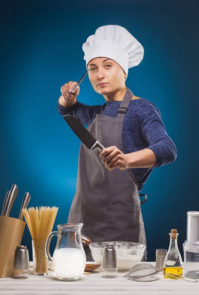 Woman Chef prepares a delicious dish on a blue background. — Stock Photo, Image