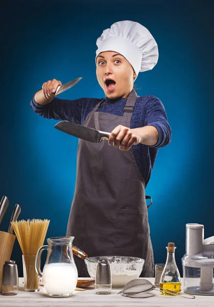 Mujer Chef prepara un delicioso plato sobre un fondo azul . — Foto de Stock