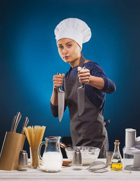 Woman Chef prepares a delicious dish on a blue background. — Stock Photo, Image