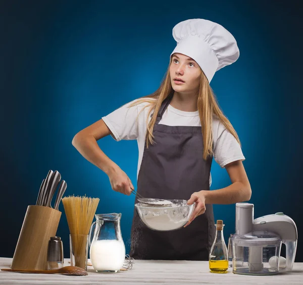 Donna Chef prepara un delizioso piatto su sfondo blu . — Foto Stock