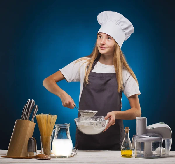 Donna Chef prepara un delizioso piatto su sfondo blu . — Foto Stock