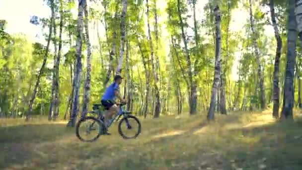 Jeune homme faisant du vélo sur une route forestière dans un jour de sammer — Video