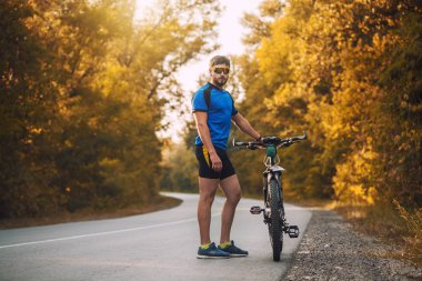 Sakallı adam dağ bisikletiyle ormanda bisiklet sürüyor..