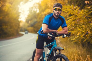 Sakallı adam dağ bisikletiyle ormanda bisiklet sürüyor..