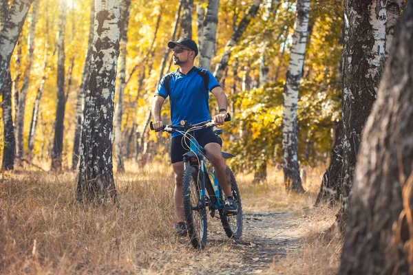 Man met baard fietser rijdt in het bos op een mountainbike. — Stockfoto