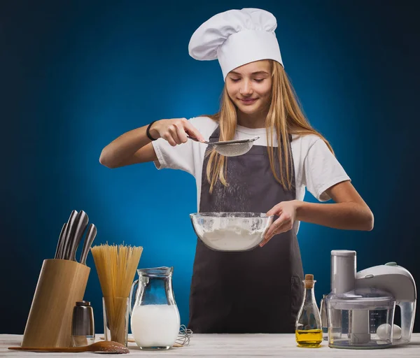 Vrouw Chef bereidt een heerlijk gerecht op een blauwe achtergrond. — Stockfoto