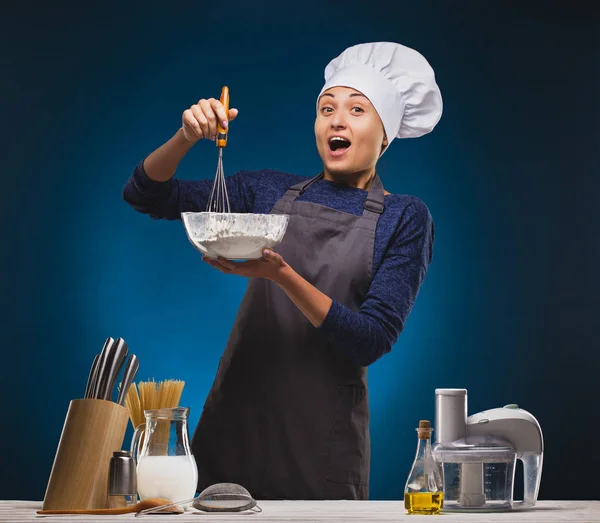Woman Chef prepares a delicious dish on a blue background. — Stock Photo, Image