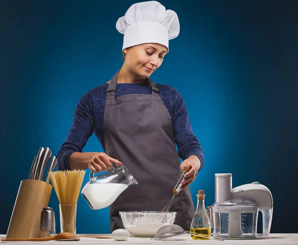 Woman Chef prepares a delicious dish on a blue background. — Stock Photo, Image