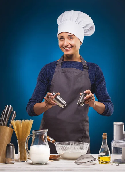 Woman Chef prepares a delicious dish on a blue background. — Stock Photo, Image