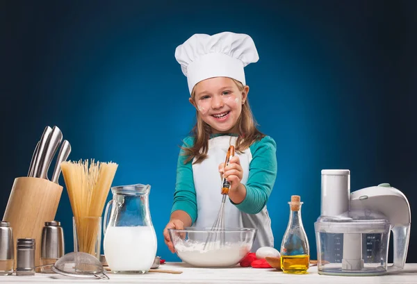 Menina Chef prepara um delicioso prato em um fundo azul . — Fotografia de Stock