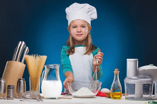 Menina Chef prepara um delicioso prato em um fundo azul . — Fotografia de Stock