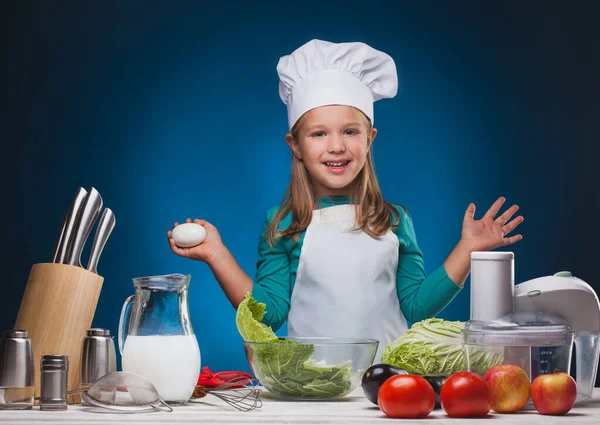 Köchin bereitet ein köstliches Gericht auf blauem Hintergrund zu. — Stockfoto