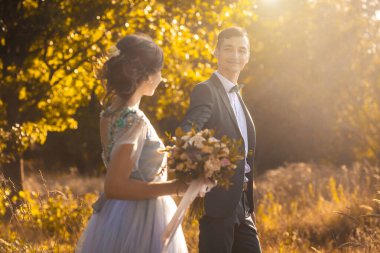 Yeni evliler yeşil parkta yürüyor.