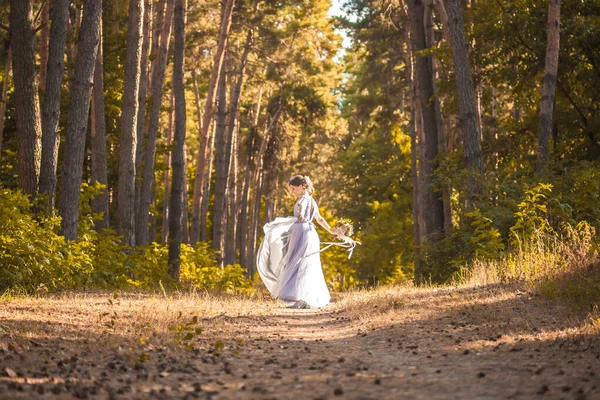 新娘拿着花束走在绿色的公园里 — 图库照片