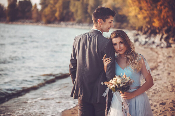 newlyweds are walking on the autumn beach