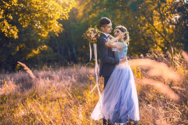 Yeni evliler yeşil parkta yürüyor.