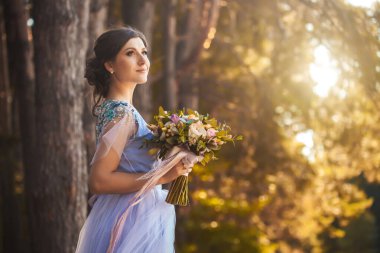 Çiçekli gelin yeşil parkta yürüyor.