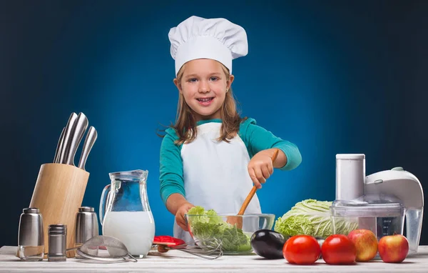 Girl Chef prepares a delicious dish on a blue background. — Stock Photo, Image