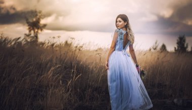 Çiçekli gelin çayırda yürüyor.