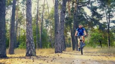 Sakallı adam dağ bisikletiyle ormanda bisiklet sürüyor..