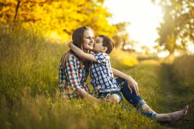 Anne ve oğlu yeşil bir çayırda oynuyorlar. Parkta aktif yürüyüş