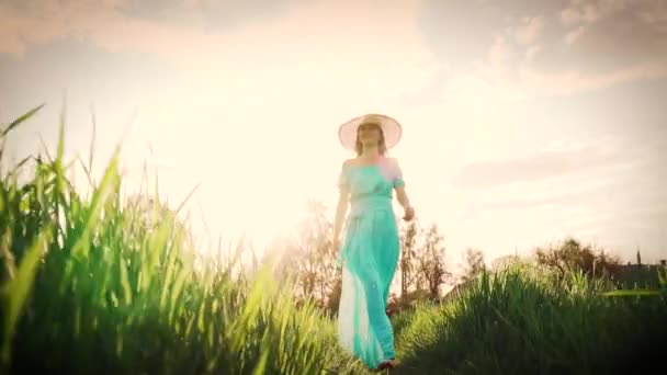 Mladá žena kráčí po pšeničném poli s východem slunce na pozadí — Stock video