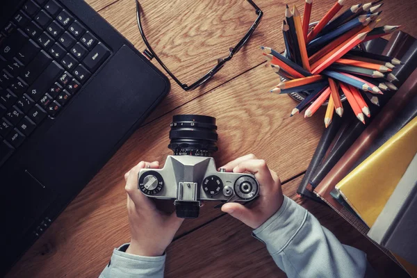 Desktop malého dětského fotografa. pohled shora. Fotoaparát a notebook na dřevěném stole — Stock fotografie