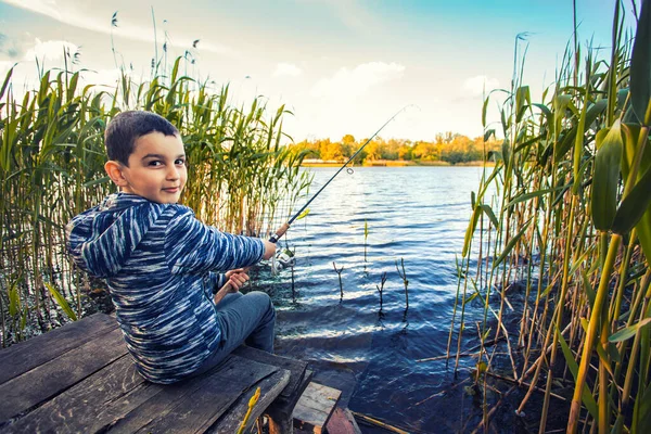 Mignon garçon capture des poissons sur un lac d'été. — Photo
