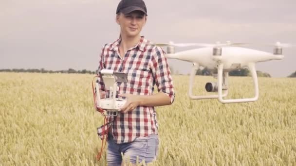 Caminante mujer caminando en el campo con dron volando sobre tierras de cultivo al atardecer — Vídeos de Stock