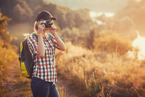 带着背包和照相机的女游客穿过风景如画的草地 给风景如画的风景拍照 户外活动 — 图库照片