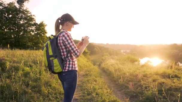 Tourist woman with a backpack and a camera walks through a picturesque meadow. — Stock Footage Tourist woman with a backpack and a camera walks through a picturesque meadow. Stock Footage