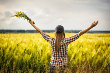 Gün batımına karşı buğday tarlasında mutlu bir kadın. özgürlük kavramı