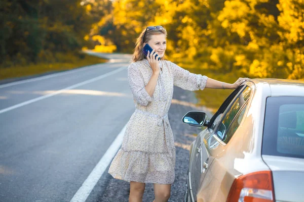 예쁜 금발의 금발의 여성이 차 근처에서 전화를 하는 모습. — 스톡 사진