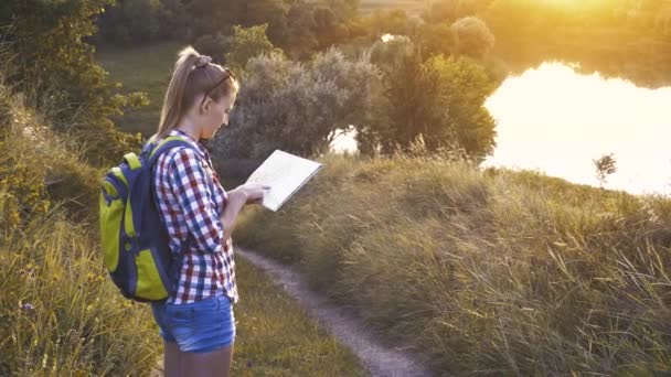 Női turista térképpel és hátizsákkal a túrán navigál a terepen. Szabadidő — Stock videók