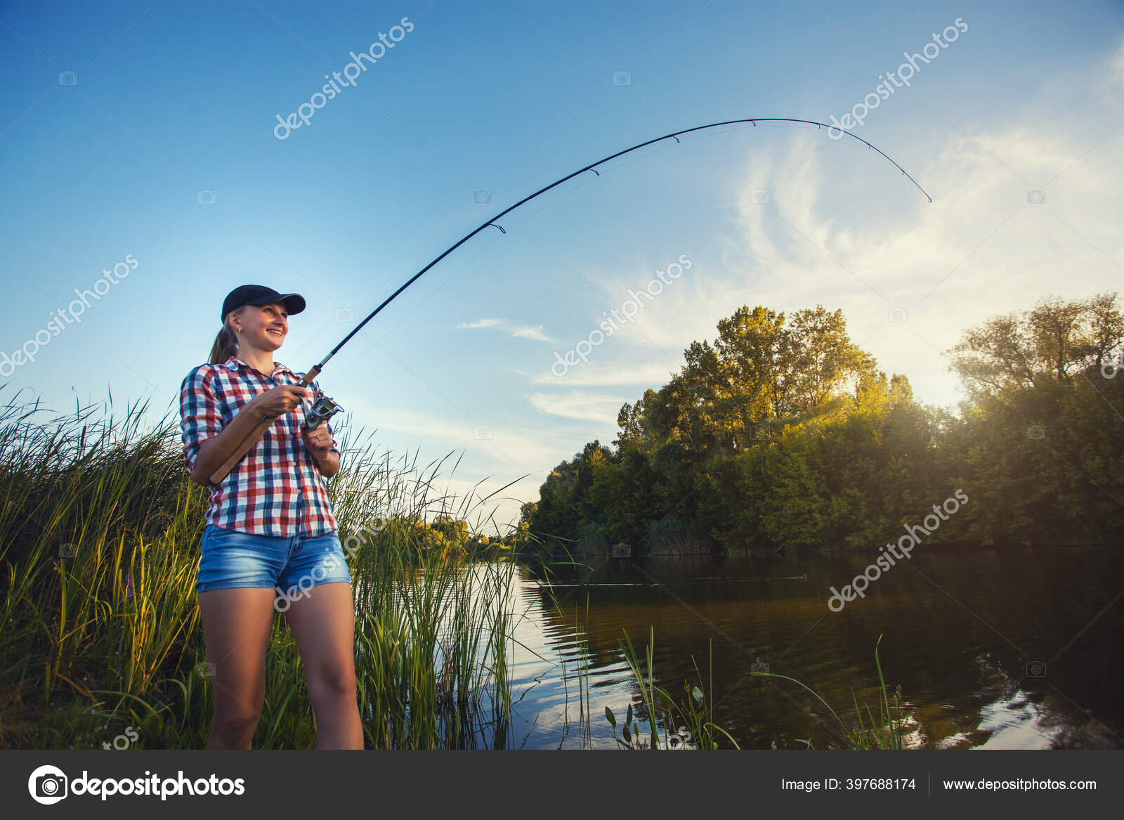 Cute woman is fishing with rod on lake Stock Photo by ©titov 397688174